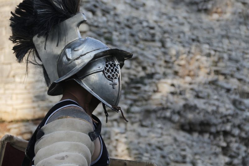 「ローマ帝国時代」風の甲冑鎧とマスクを着用した兵士の横向き写真。