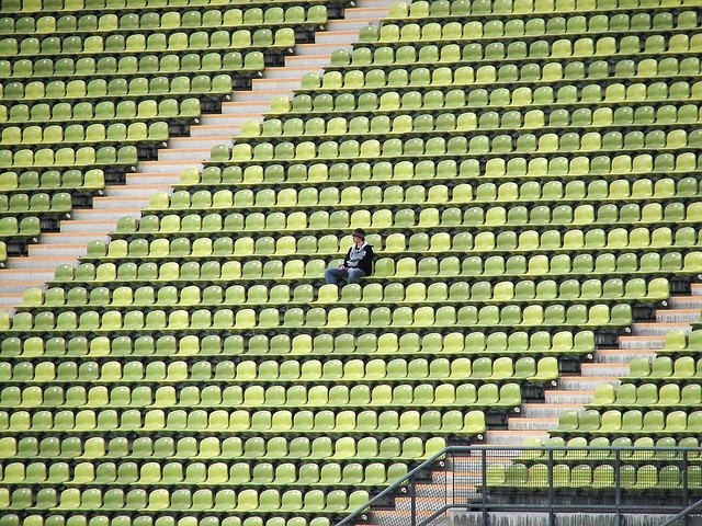 ほぼ空っぽ（無観客）の巨大スタジアムに１人だけ観客が座っている写真。